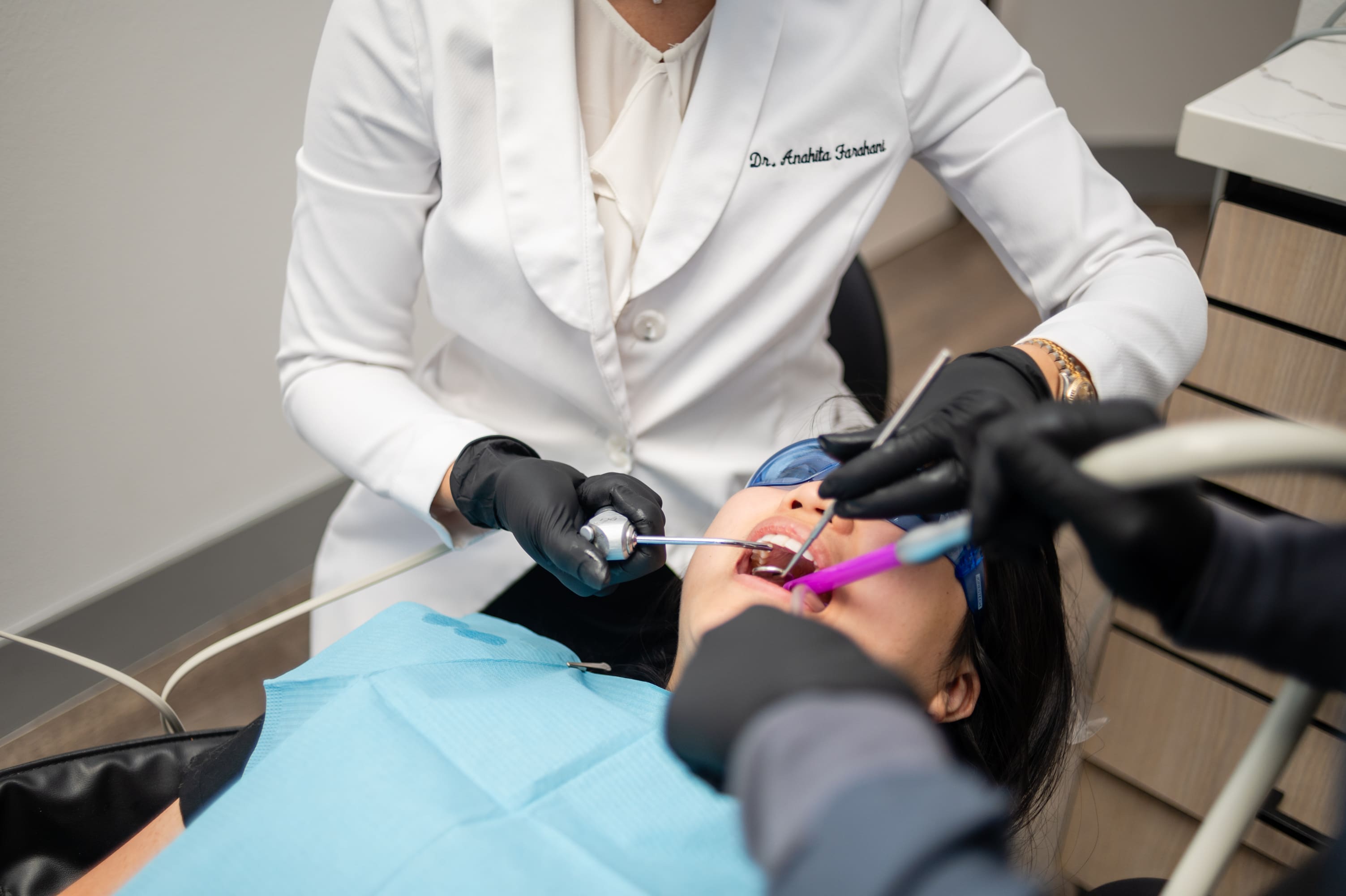 A dentist is using an electric toothbrush to brush the teeth of a patient.