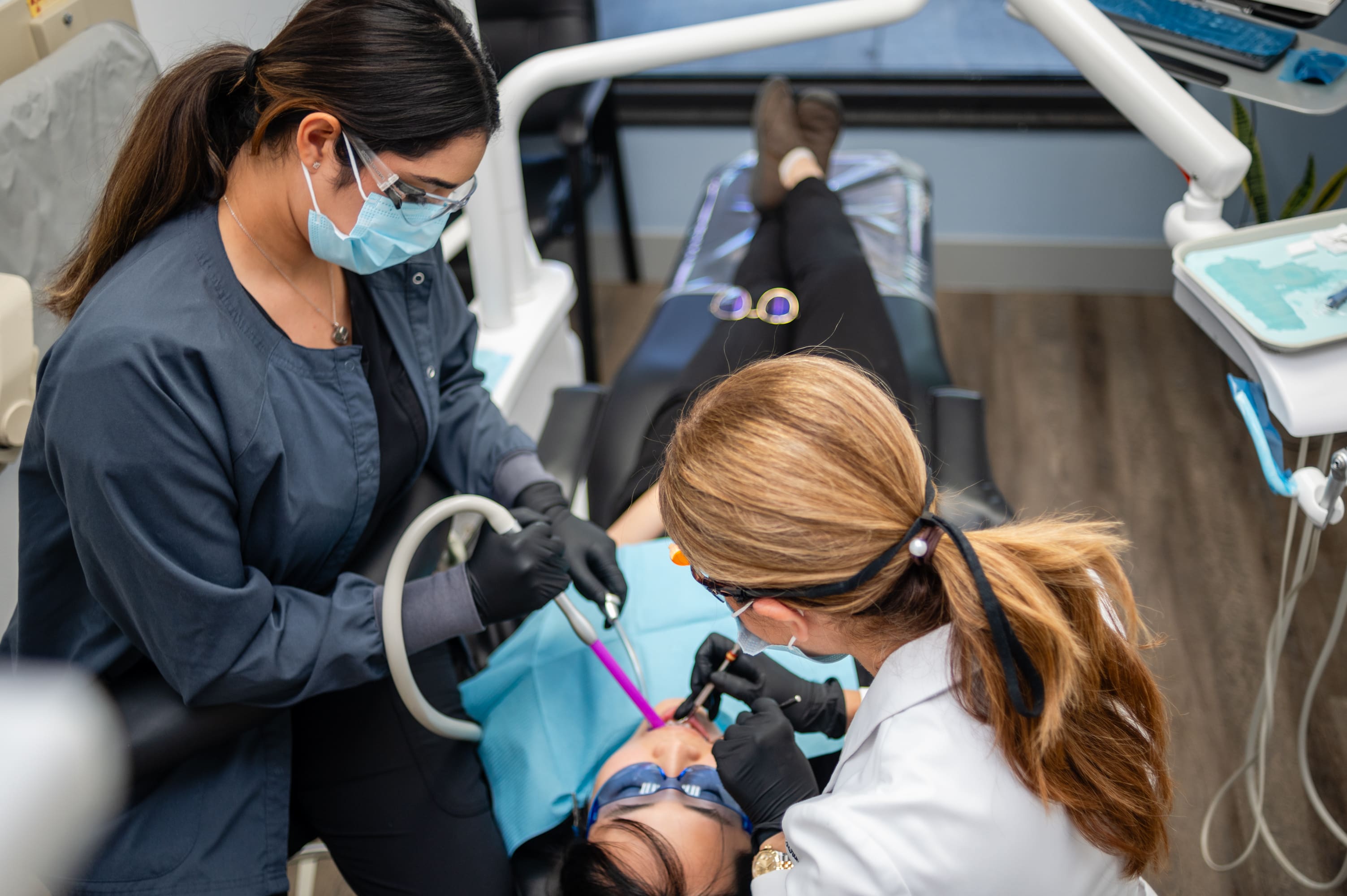 A woman is getting her teeth brushed by another person.